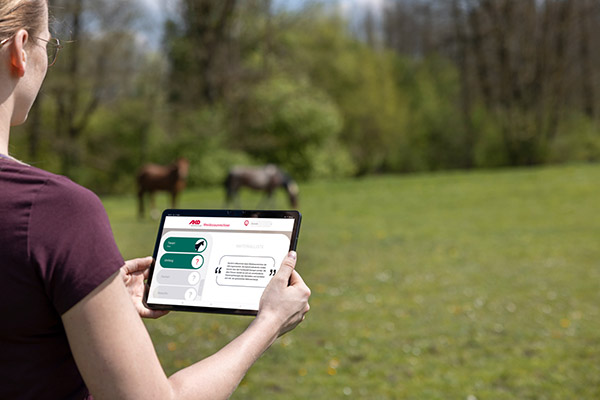 Frau betrachtet den AKO Weidezaunrechner auf dem Tablet