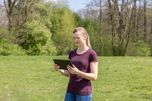 Landwirtin plant mit dem AKO Weidezaunrechner auf einem Tablet